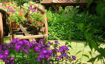 a lush green garden with a wooden gazebo and vibrant flowers , providing a serene and peaceful atmosphere at Auberge la Tomette, the Originals Relais