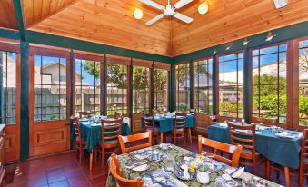 a dining room with a table set for breakfast , surrounded by windows that offer a view of the outdoors at Victoria House