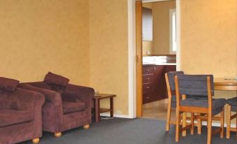 a living room with a couch , chair , and dining table in front of a door at Cedar Lodge Motel