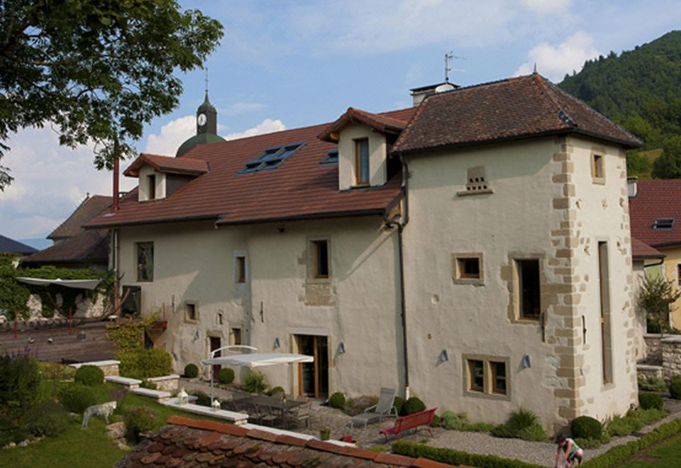 a large , old stone house with a red roof and a fountain in front of it at Le Manoir