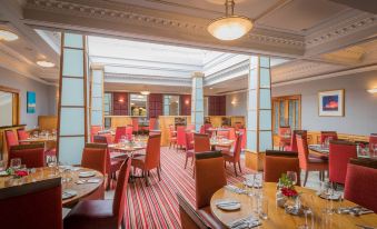 a well - lit restaurant with multiple dining tables and chairs arranged for guests to enjoy their meal at Slieve Russell Hotel