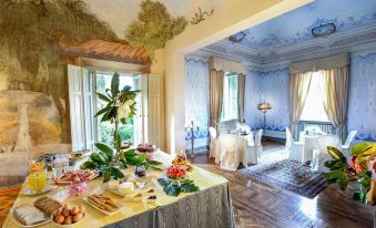 a luxurious hotel room with a dining table set up for a meal , surrounded by various food items and decorations at Villa Alta - Residenza d'Epoca Con Piscina