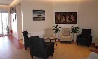 a modern waiting room with multiple chairs , tables , and paintings on the walls , creating a comfortable and inviting atmosphere at Hotel Flokalundur