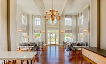 a large , white - walled room with high ceilings and wooden floors , containing several rows of tables and chairs arranged for dining at The Equinox