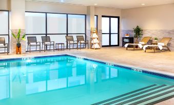 a large swimming pool with a lounge area and sun loungers in the background , all surrounded by windows at Crowne Plaza Boston - Woburn, an IHG Hotel