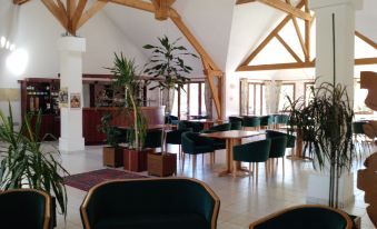 a large , open room with wooden beams on the ceiling , containing a dining area and several chairs at Logis Hotel Restaurant de l'Abbaye