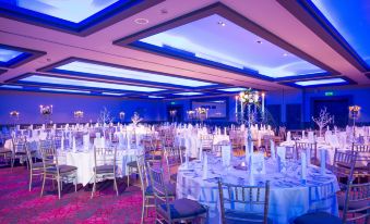 a large banquet hall with multiple tables set for a formal event , featuring white tablecloths and chairs at Oriel House Hotel