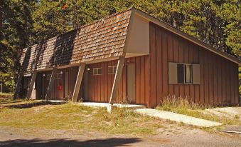 a wooden building with a sloping roof , situated in a wooded area near a road at Lake Lodge