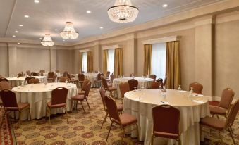 a large , well - lit conference room with multiple round tables and chairs arranged for a formal event at Hilton St. Louis Frontenac