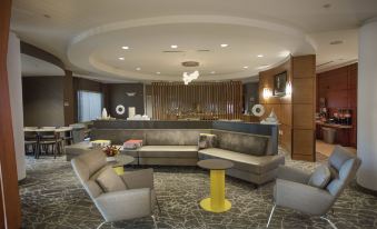 a modern living room with gray sofas , yellow tables , and a circular bar in the center at SpringHill Suites Athens West