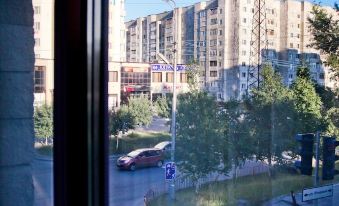 a view from a window , looking out at a busy city street with tall buildings and a large truck passing by at Yugorsky
