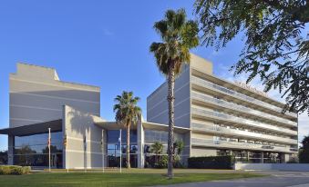 a modern , white building with multiple balconies and palm trees in front of it , under a clear blue sky at Sol Costa Daurada