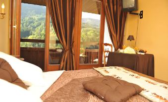 a well - decorated bedroom with a view of the mountains through large windows , a comfortable bed , and a tv at La Cascade