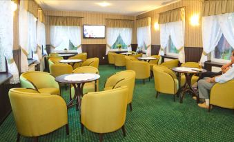 a conference room with yellow chairs , green carpet , and a television mounted on the wall at Millennium Spa
