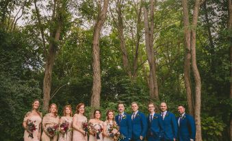 a group of people , including a bride and groom , are posing for a photo in front of a forest at The Bond 1835