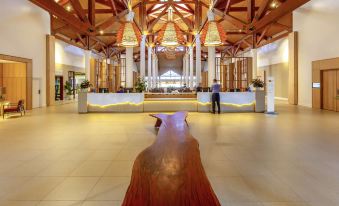 a large , well - lit lobby with a wooden sculpture on display , and a person standing near the entrance at Novotel Sunshine Coast Resort