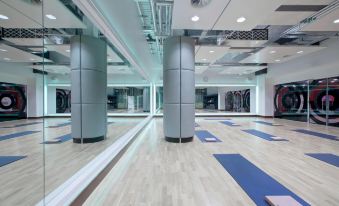 a large , modern gym with multiple yoga mats placed on the floor and a mirror hanging on the wall at London Twickenham Stadium Hotel, a Member of Radisson Individuals