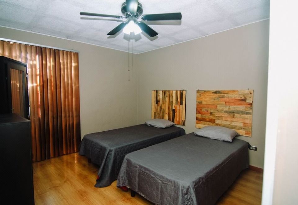 a bedroom with two beds , a ceiling fan , and a fan on the left side at La Esperanza