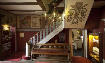 a wooden bench is situated in a room with a red carpet and ornate chandelier at Hotel Dagmar