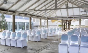 an outdoor event space with white chairs and blue cushions set up under a covered area at Marriott Albuquerque