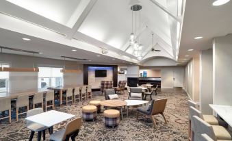 a modern , well - lit restaurant with high ceilings and a large dining table in the center , surrounded by chairs at Residence Inn New Bedford Dartmouth