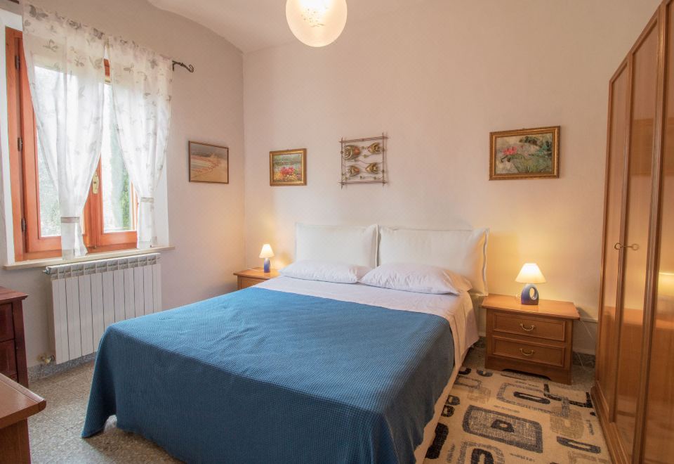 a cozy bedroom with a blue bedspread , white walls , and two lamps on either side of the bed at Olimpia