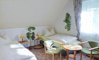 a cozy bedroom with two beds , a small table and chairs , and plants on the window sill at Zerna