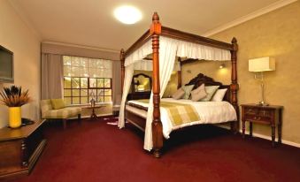 a large bed with a wooden frame and white canopy is in the center of a room with red carpeting at Inn Mahogany Creek