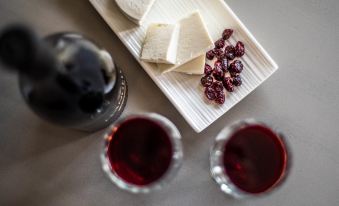 a table with two wine glasses , a bottle of wine , and some cheese and dried fruits at Azure