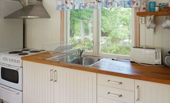 a well - equipped kitchen with white cabinets , wooden countertops , and stainless steel appliances under a window at Simrishamn