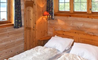 a cozy wooden cabin bedroom with two twin beds , a window , and curtains , under natural light at Olden