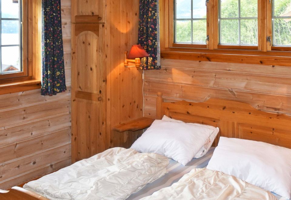 a cozy wooden cabin bedroom with two twin beds , a window , and curtains , under natural light at Olden