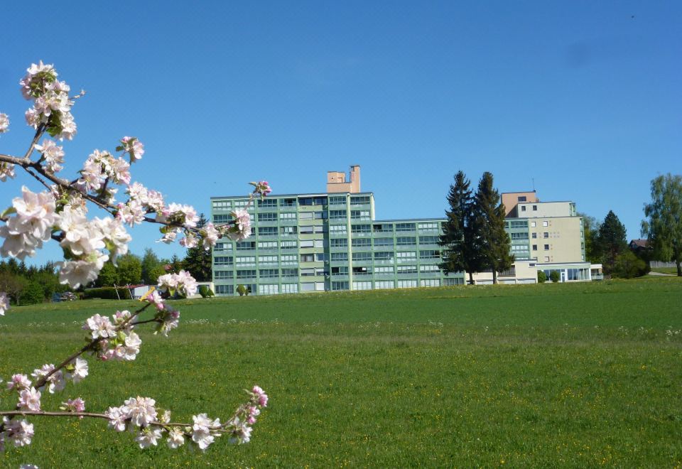 a large , modern building with a green lawn and clear blue skies in the background at B 94