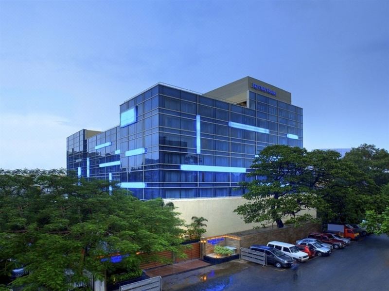 a modern building with blue glass windows and a car parked in front of it at Taj Club House