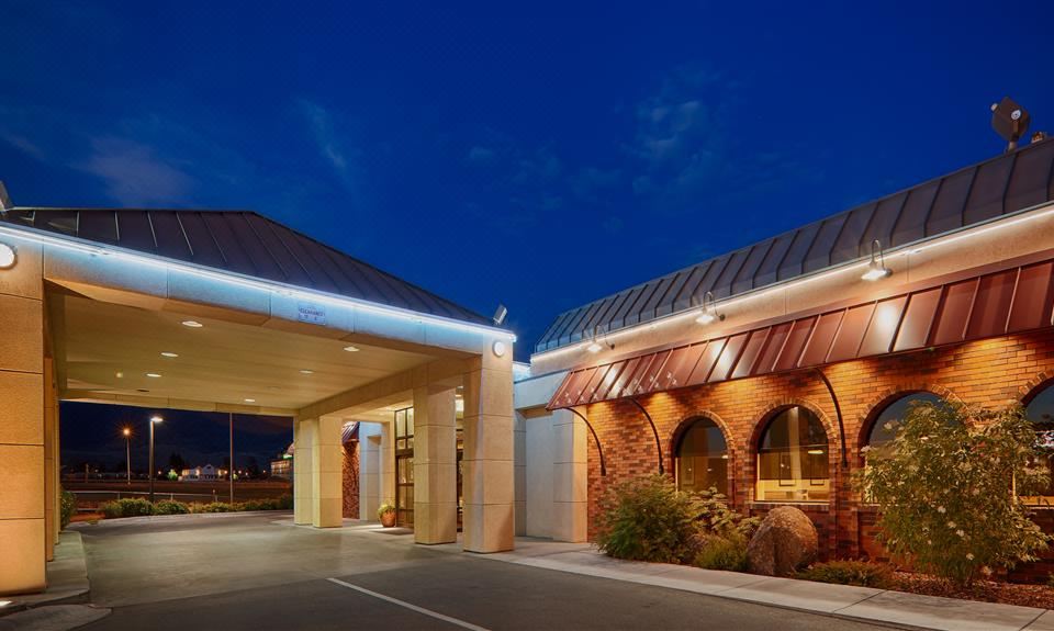 a large building with a brick exterior and a red roof is lit up at night at Best Western Plus Butte Plaza Inn