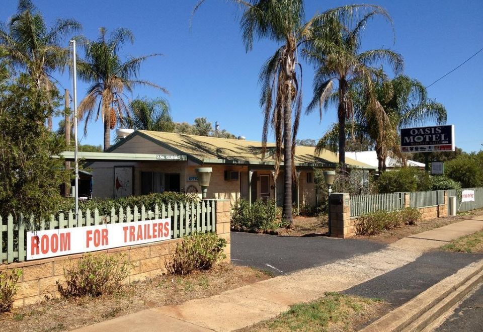 "a small house with palm trees and a sign that says "" home for trailers "" in front of it" at Oasis Motel