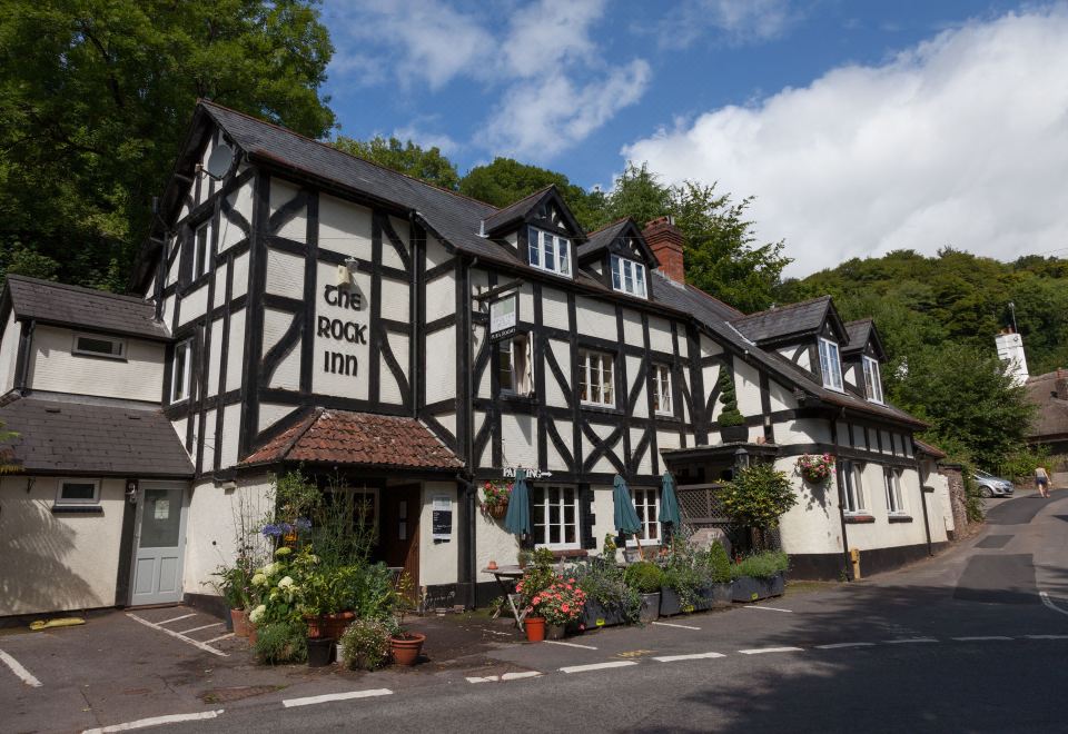 "a quaint black and white building with a sign that reads "" the book inn "" is surrounded by trees" at Rock Inn