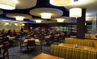 a large dining area with multiple tables and chairs , some of which are covered in striped tablecloths at Hotel San Sebastian