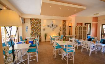 a dining room with white tables and chairs , blue cushions , and a colorful wall design at Amazona