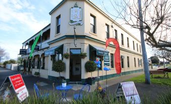 a building with a green and red awning is surrounded by potted plants and chairs at Seaview House