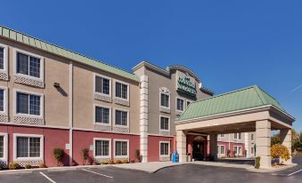 a holiday inn express hotel with its green roof , red walls , and white signage , standing under a clear blue sky at La Quinta Inn & Suites by Wyndham Knoxville North I-75