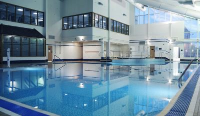 an empty swimming pool with a large window and balcony , set in an indoor facility at Village Hotel Liverpool