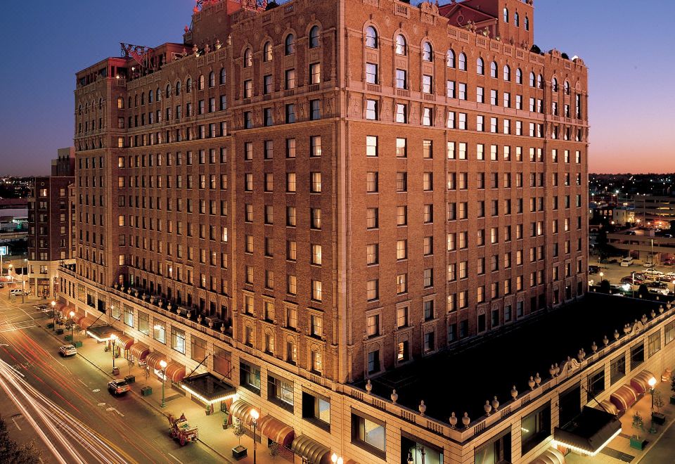 a large brick building with a red and white sign on top is surrounded by trees and other buildings at Peabody Memphis