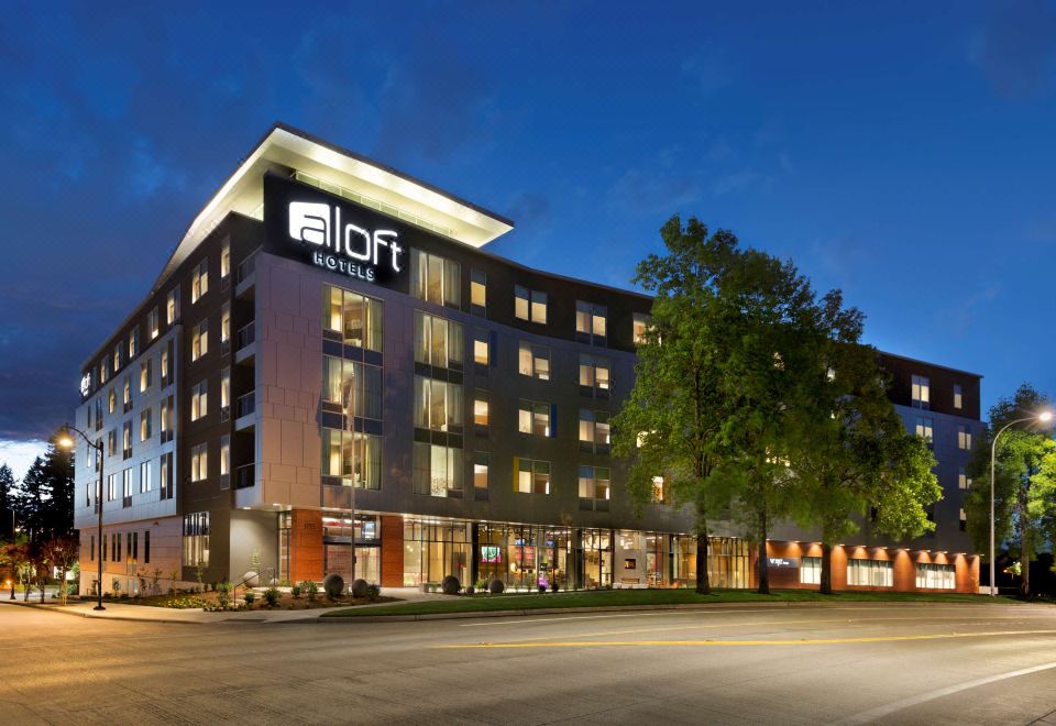 "a large building with the words "" hotel "" on it is lit up at night , and trees in the background" at Aloft Hillsboro-Beaverton