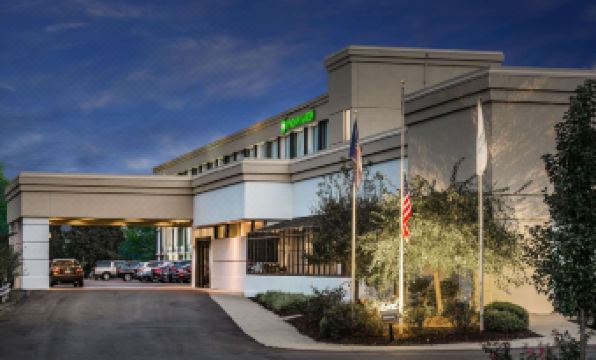 a large hotel with a green sign and flags flying in front of the entrance at Wyndham Garden Pittsburgh Airport