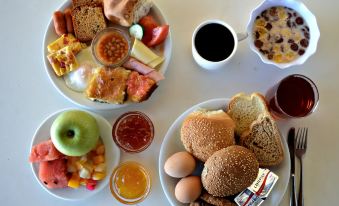 a table is set with two plates of breakfast food , including bread , eggs , fruit , and coffee at Paradise Beach Hotel