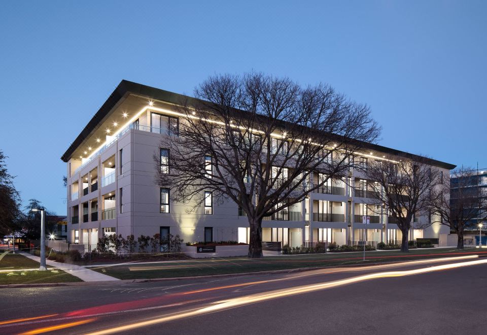 a large building with a modern design , situated on a street corner under the night sky at Knightsbridge Canberra