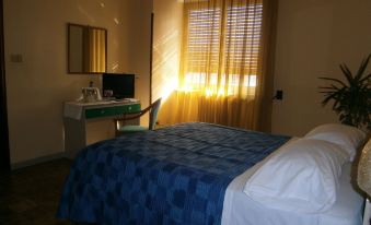 a hotel room with a blue and white bedspread , a tv on a desk , and curtains at Hotel Sole