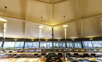 a modern dining room with wooden tables and chairs arranged in a spacious setting , surrounded by large windows that offer views of the outdoors at Discovery Resorts - Kings Canyon