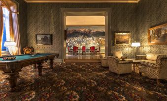 a pool table is in the center of a room with chairs and a large mural on the wall at Grandhotel Giessbach